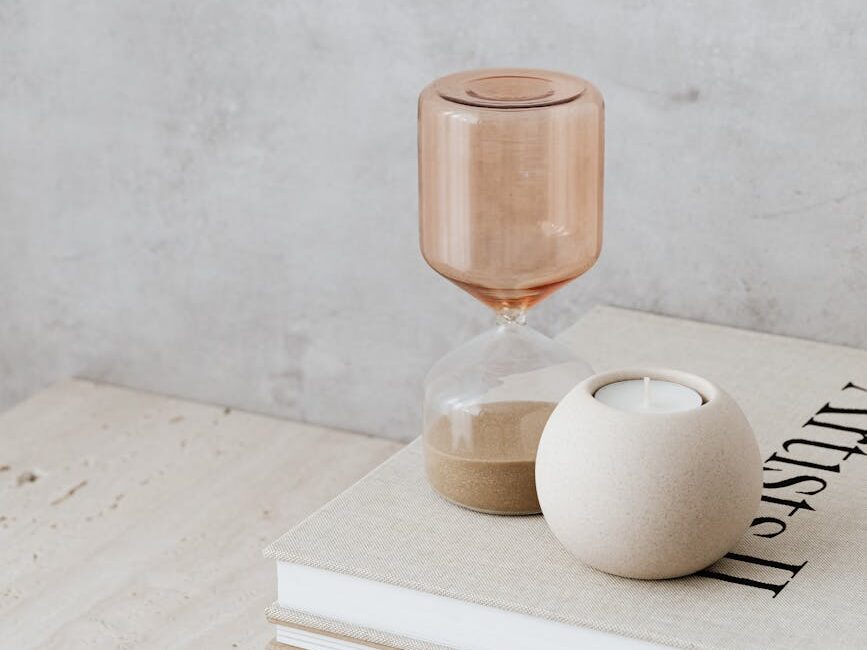 minimalist still life with beige hourglass and a candle on books